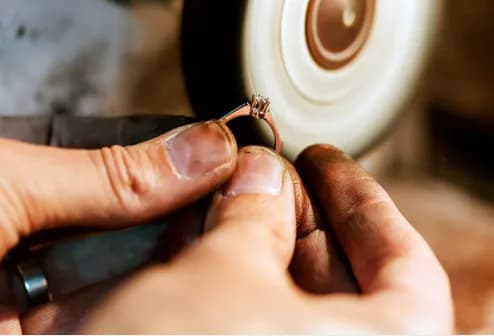 Jeweller's hands polishing a gold diamond ring to a mirror finish with a rotary tool