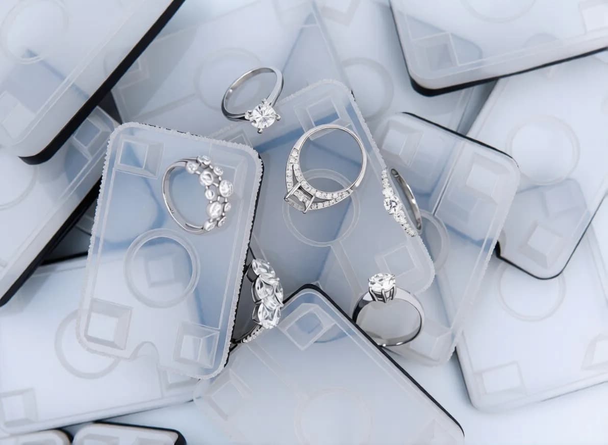 Translucent RTV silicone moulds holding finished diamond rings, stacked ready for wax injection